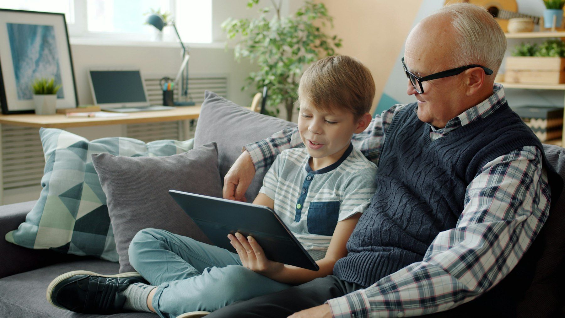 Un grand-père et son petit-fils regardent des photos sur une tablette